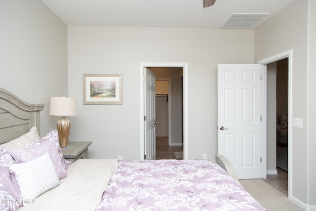 bedroom with light colored carpet, visible vents, a spacious closet, a ceiling fan, and baseboards