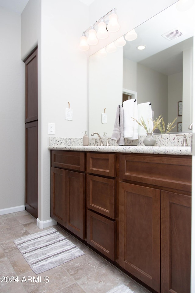 full bathroom with double vanity, baseboards, and visible vents