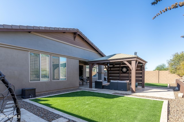 rear view of house featuring outdoor lounge area, a gazebo, a patio, and a lawn