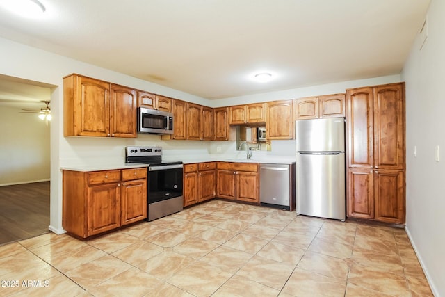 2227 N 57th Dr, Phoenix, AZ 85035 - kitchen with stainless steel appliances, light countertops, a sink, a ceiling fan, and brown cabinetry