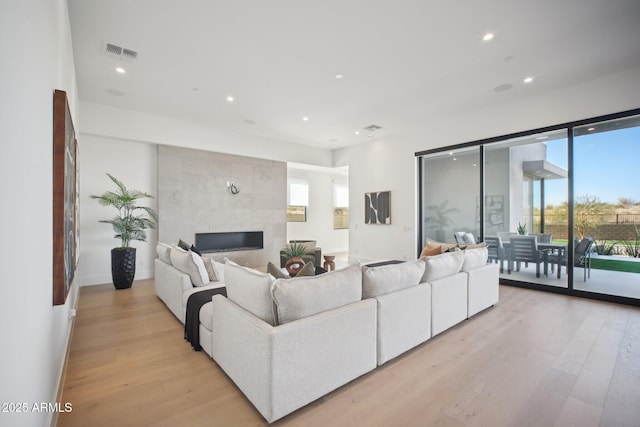 living room featuring light wood-type flooring and a tiled fireplace