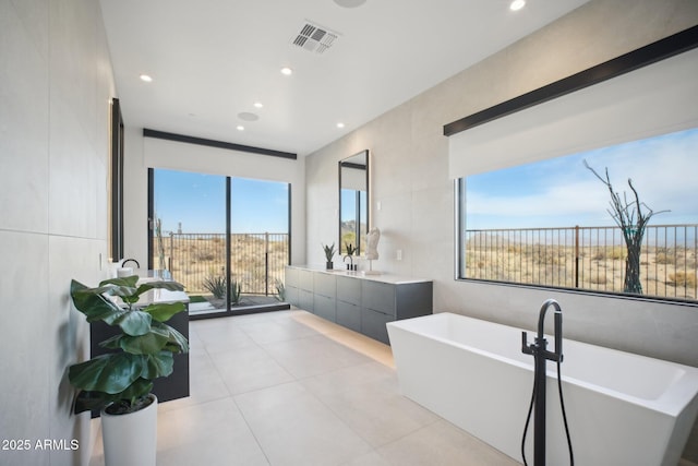 bathroom featuring a wealth of natural light, vanity, tile patterned floors, and a bathtub