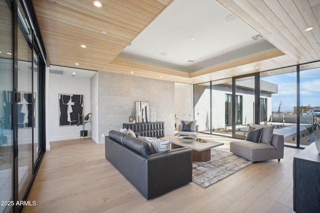 living room featuring a tray ceiling, light hardwood / wood-style flooring, floor to ceiling windows, and wooden ceiling