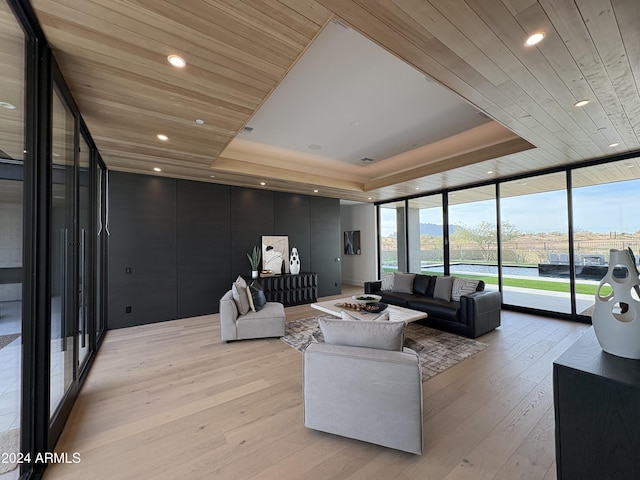 living room with light hardwood / wood-style flooring, a raised ceiling, floor to ceiling windows, and wooden ceiling