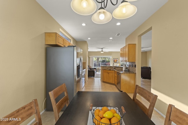 kitchen featuring pendant lighting, light tile patterned floors, dark stone countertops, stainless steel appliances, and kitchen peninsula