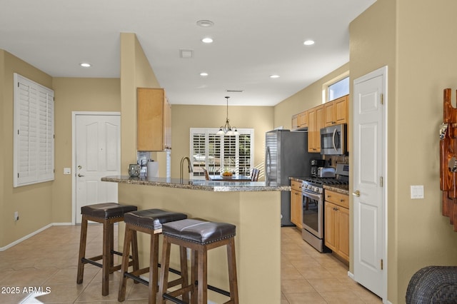 kitchen featuring pendant lighting, a kitchen bar, stainless steel appliances, light tile patterned flooring, and kitchen peninsula