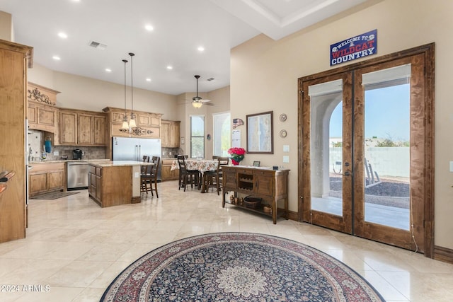 interior space featuring plenty of natural light, a center island, decorative light fixtures, and french doors