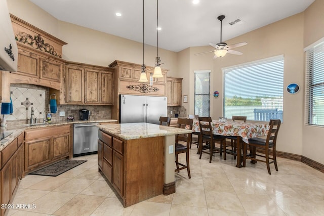 kitchen featuring sink, decorative backsplash, appliances with stainless steel finishes, decorative light fixtures, and a kitchen island