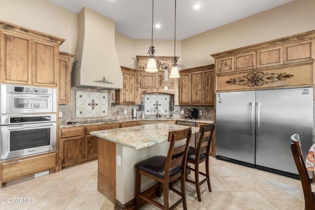 kitchen featuring appliances with stainless steel finishes, light stone counters, custom exhaust hood, pendant lighting, and a kitchen island