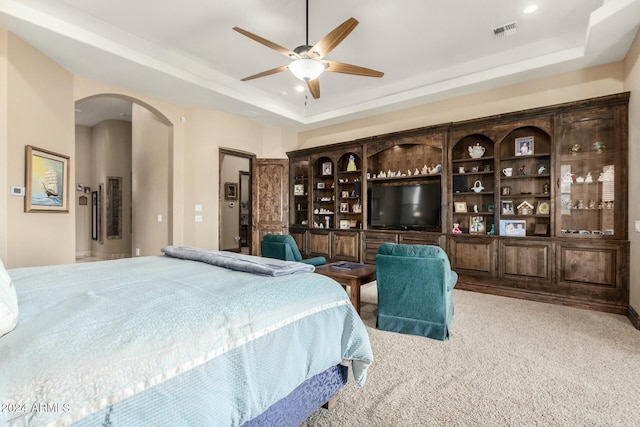 carpeted bedroom featuring ceiling fan and a tray ceiling