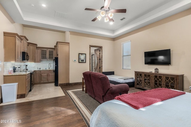 living room featuring a raised ceiling, ceiling fan, sink, and light wood-type flooring