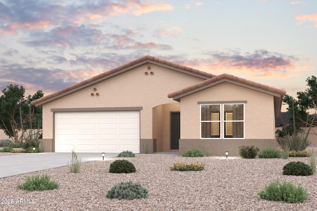 view of front of property with driveway, an attached garage, a tiled roof, and stucco siding