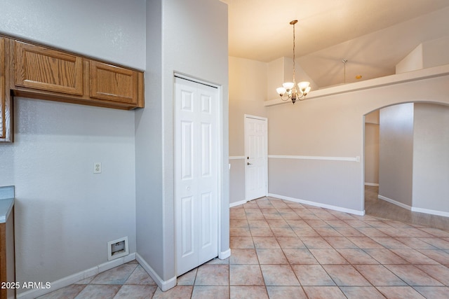 kitchen with lofted ceiling, pendant lighting, a notable chandelier, and light tile patterned floors