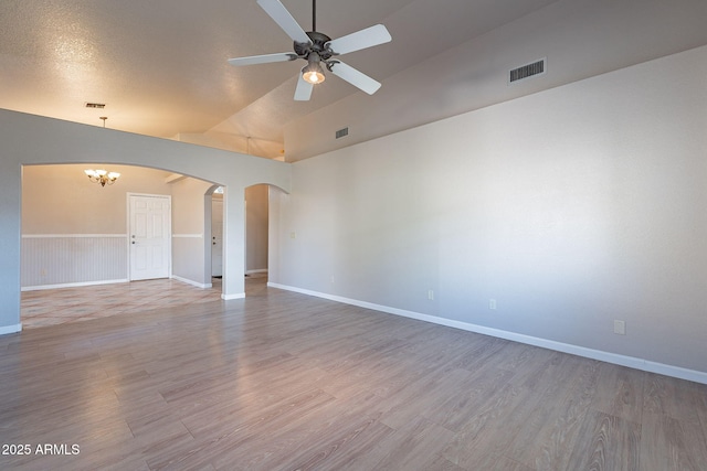 spare room featuring vaulted ceiling, ceiling fan with notable chandelier, and hardwood / wood-style floors