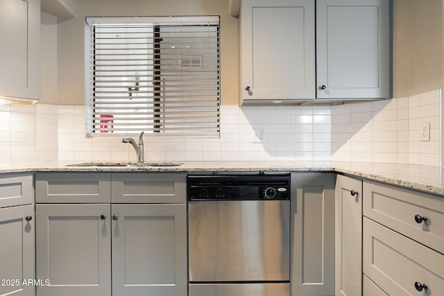 kitchen featuring light stone countertops, stainless steel dishwasher, gray cabinetry, and sink