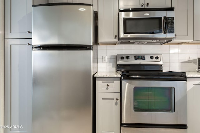 kitchen with tasteful backsplash, light stone counters, and stainless steel appliances