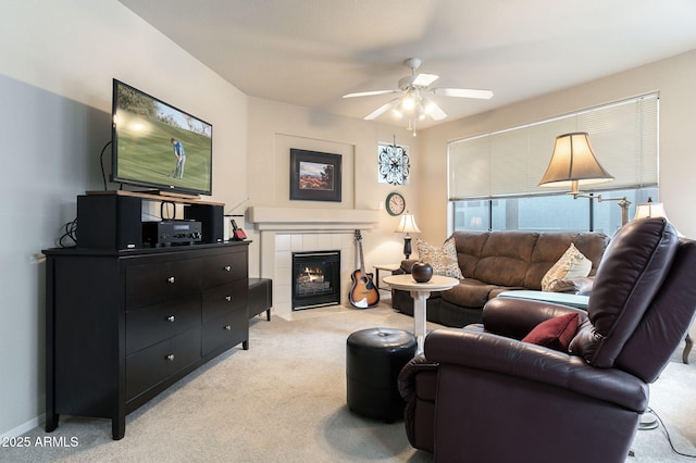 carpeted living room with a tile fireplace and ceiling fan