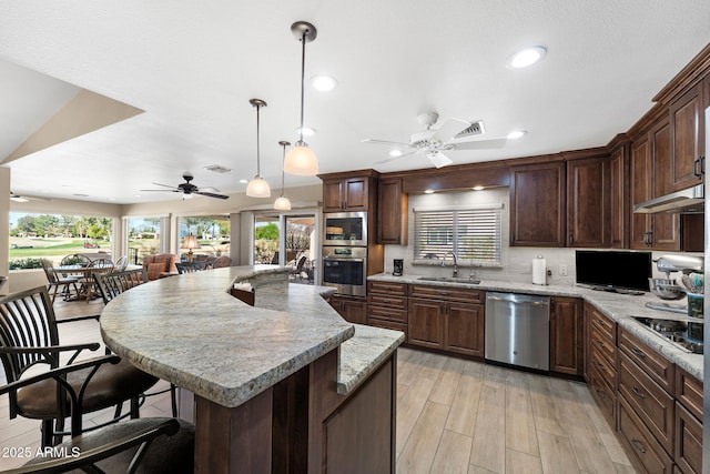 kitchen with a center island, light wood-style flooring, appliances with stainless steel finishes, a kitchen breakfast bar, and a sink