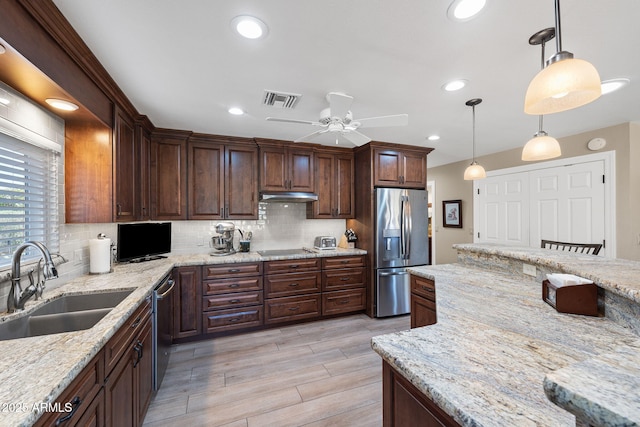 kitchen featuring visible vents, a sink, stainless steel appliances, under cabinet range hood, and backsplash