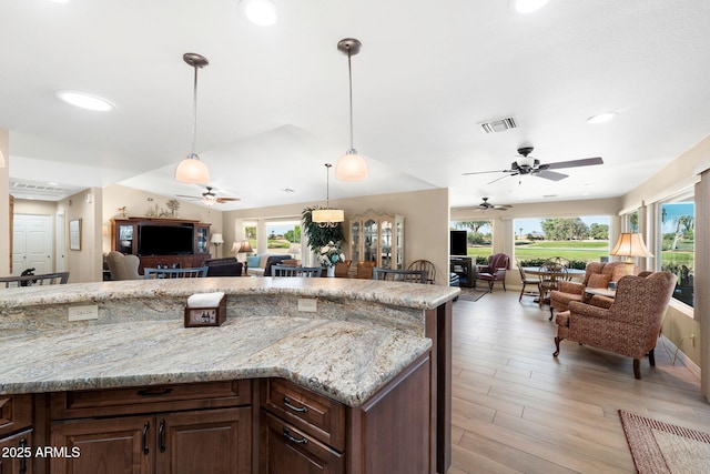 kitchen with plenty of natural light, light stone countertops, and open floor plan