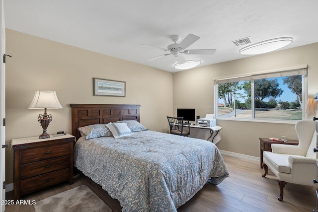 bedroom featuring visible vents, a ceiling fan, baseboards, and wood finished floors