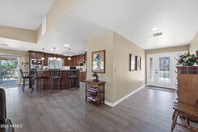 kitchen with visible vents, baseboards, appliances with stainless steel finishes, a kitchen breakfast bar, and wood finished floors