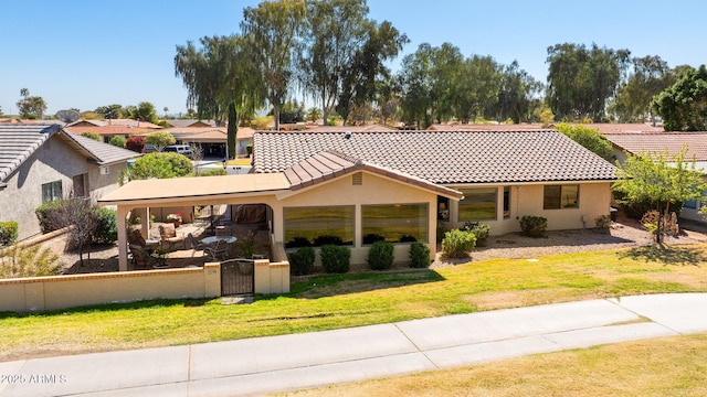 back of house featuring stucco siding, a lawn, a gate, a tile roof, and a fenced front yard