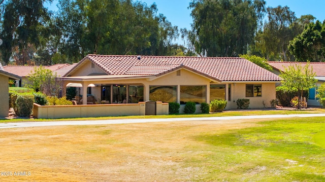 mediterranean / spanish-style home featuring stucco siding, a tile roof, and a front yard