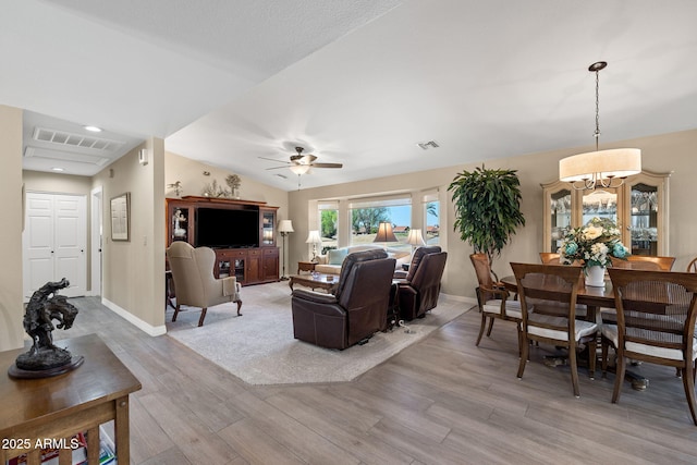 living area with vaulted ceiling, baseboards, visible vents, and light wood-type flooring