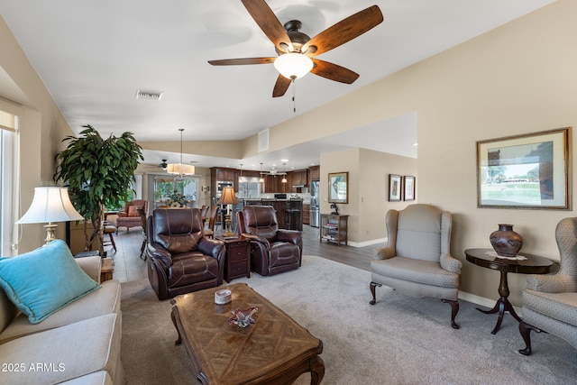 living room with visible vents, a ceiling fan, baseboards, lofted ceiling, and light colored carpet