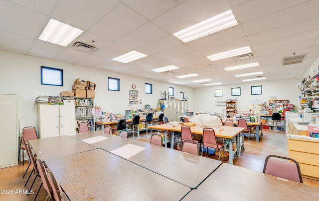 dining area with a drop ceiling, concrete floors, and visible vents