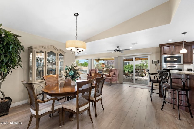 dining area with visible vents, light wood finished floors, a healthy amount of sunlight, and vaulted ceiling