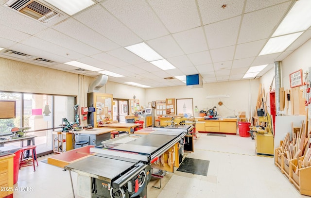 interior space featuring visible vents, light floors, a workshop area, and a paneled ceiling