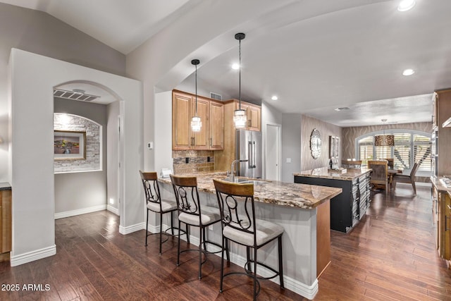 kitchen with dark wood-type flooring, a center island, vaulted ceiling, and high end refrigerator