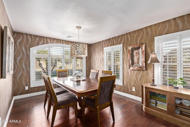 dining room with dark wood finished floors, a textured ceiling, and baseboards