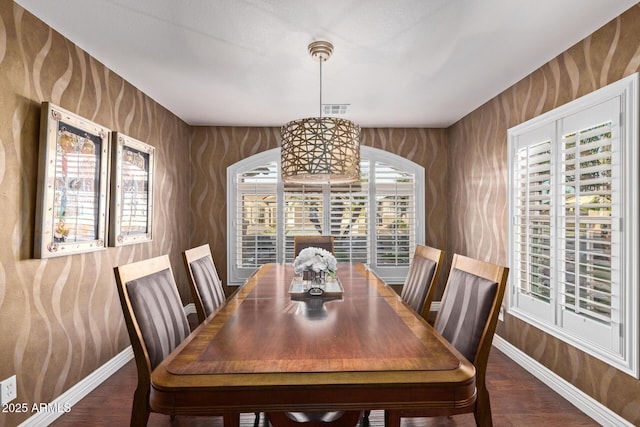 dining space with arched walkways, wood finished floors, visible vents, and baseboards