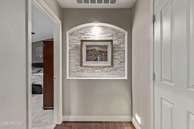 hall with baseboards, visible vents, and wood finished floors