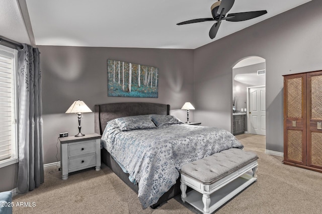 bedroom with arched walkways, ceiling fan, light colored carpet, visible vents, and baseboards