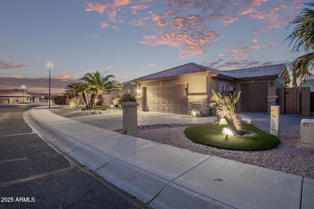 view of front of property featuring a tile roof, stucco siding, a garage, stone siding, and driveway