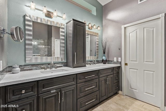 full bath with a textured wall, wood finished floors, a sink, and double vanity