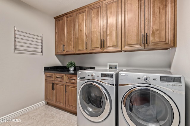 laundry area featuring cabinet space, washing machine and dryer, baseboards, and light tile patterned flooring