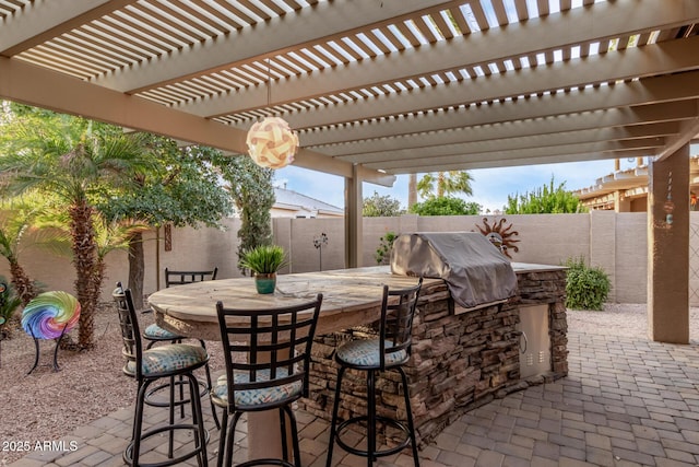 view of patio featuring exterior kitchen, a fenced backyard, and outdoor dry bar