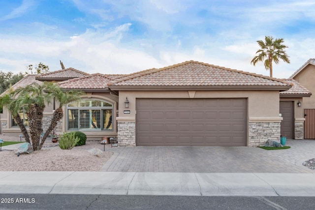 view of front facade with stone siding, decorative driveway, an attached garage, and stucco siding