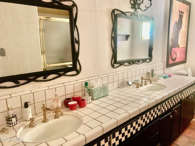 bathroom featuring tasteful backsplash, vanity, and a shower with door