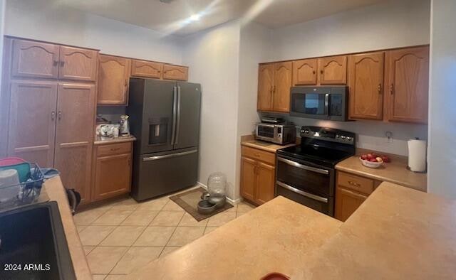 kitchen with light tile patterned floors and stainless steel appliances