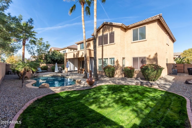 back of house featuring central AC, a yard, a fenced in pool, and a patio area