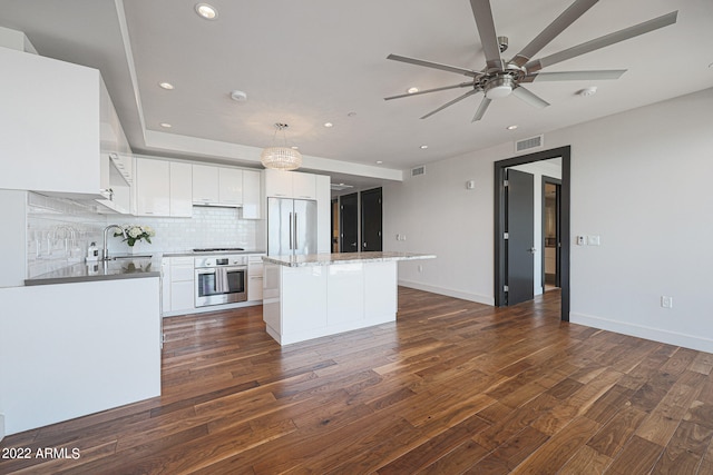 kitchen with a kitchen island, appliances with stainless steel finishes, dark wood-type flooring, and white cabinetry