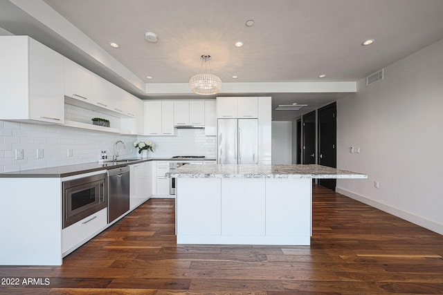 kitchen featuring a center island, dark hardwood / wood-style floors, built in appliances, sink, and white cabinets