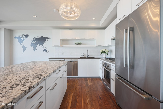 kitchen with dark wood-type flooring, white cabinets, light stone countertops, stainless steel appliances, and sink