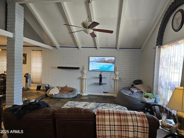 living room with vaulted ceiling with beams, a ceiling fan, brick wall, and decorative columns